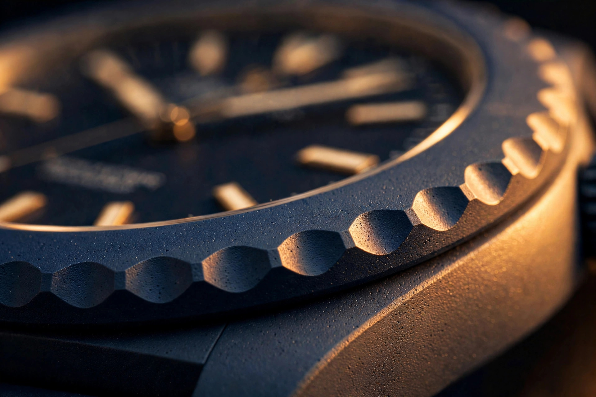 Editorial macro photograph of a matte ceramic sports watch bezel with scalloped edge detail in warm amber lighting, showing the fine grain of sintered technical ceramic