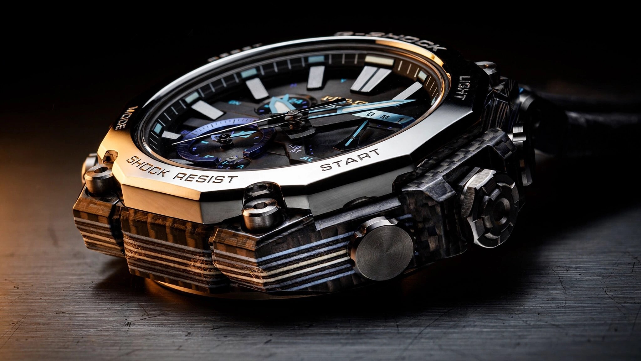 Close-up macro photograph of a G-Shock MTG-B4000 watch showing the layered carbon fiber frame edge and Sallaz-polished stainless steel bezel, warm studio lighting highlighting the laminated cross-section pattern